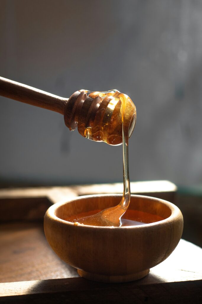 Unsplashed Beautiful golden honey on honey dipper.